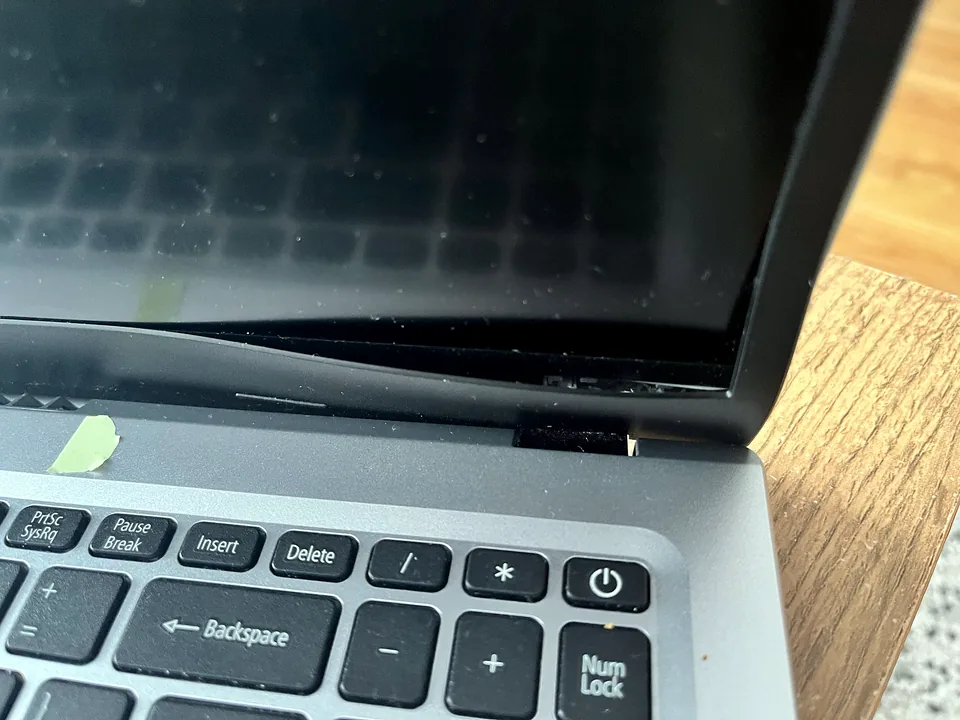 Close-up of a damaged laptop hinge and casing